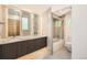 Well-lit bathroom showcasing a vanity with double sinks, a shower/tub combo with glass doors, and neutral tiling at 814 S High St, Denver, CO 80209