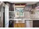 Close-up of a kitchen with stainless steel appliances, mosaic backsplash, and a farmhouse sink at 801 Hanover St, Aurora, CO 80010