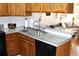 Well-lit kitchen featuring black appliances, wood cabinetry, and a stainless steel sink at 10515 W Dartmouth Ave, Lakewood, CO 80227