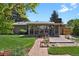 Well-maintained backyard featuring a sunroom, mature trees, landscaping, and a brick walkway at 2301 Dunbar Ct, Longmont, CO 80501