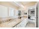 Bright bathroom featuring double sinks with granite counters, white cabinets, and a view into the bedroom at 8156 E 35Th Ave, Denver, CO 80238
