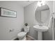 This cozy powder room features a pedestal sink, oval mirror, and decorative artwork at 9756 Mount Kataka Pt, Littleton, CO 80125