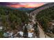 Aerial view captures the home nestled in a mountain setting with a fiery sunset sky at 11531 S Deer Creek Rd, Littleton, CO 80127