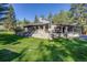 Spacious backyard featuring stone patio, well-manicured lawn, and covered seating area for leisure at 11531 S Deer Creek Rd, Littleton, CO 80127