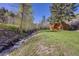 Creek flowing near a small shed in a lush yard with mature trees on a bright, sunny day at 11531 S Deer Creek Rd, Littleton, CO 80127