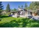 A multi-story home featuring stone accents, a spacious patio, and a well-maintained lawn with mature trees at 11531 S Deer Creek Rd, Littleton, CO 80127