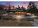 Captivating home exterior illuminated at dusk with stone accents and large windows offering stunning views of the natural surroundings at 11531 S Deer Creek Rd, Littleton, CO 80127