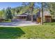 Well-maintained home with a spacious driveway, covered porch, stone accents, and lush greenery surrounding the property at 11531 S Deer Creek Rd, Littleton, CO 80127