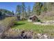 Exterior view of a charming cottage with lush lawn and tranquil creek in a serene setting at 11531 S Deer Creek Rd, Littleton, CO 80127