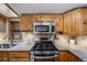 Cozy kitchen featuring wooden cabinetry, granite countertops, stainless steel appliances, and ample natural light at 11531 S Deer Creek Rd, Littleton, CO 80127