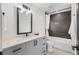 Stylish bathroom featuring gray vanity, modern fixtures, bathtub with shower and dark tile at 535 Josephine St, Denver, CO 80206