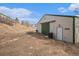 Outbuilding with green doors and weathered features, nestled into a hillside at 5774 Sioux Dr, Sedalia, CO 80135