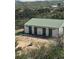 Outbuilding with a green roof and sliding doors nestled in a green and hilly area at 5774 Sioux Dr, Sedalia, CO 80135