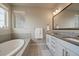 Bright bathroom features a soaking tub, double sinks, gray tiled backsplash, and a window bringing in natural light at 6747 W Jewell Pl, Lakewood, CO 80227