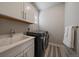 Laundry room with black washer and dryer and white cabinets at 6747 W Jewell Pl, Lakewood, CO 80227