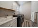 Laundry room with black washer and dryer and white cabinets at 6747 W Jewell Pl, Lakewood, CO 80227