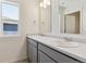 Bathroom featuring dual sinks, grey cabinetry, and a bright window at 2256 Base St, Fort Lupton, CO 80621