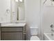 Neutral bathroom featuring a gray vanity, white sink, and shower with a white tile surround at 2256 Base St, Fort Lupton, CO 80621