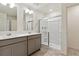 A spacious bathroom featuring dual sinks, grey cabinetry, and a glass enclosed shower at 2256 Base St, Fort Lupton, CO 80621