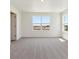 Bedroom features tan carpet, white walls and trim, and a window showing the neighborhood at 2256 Base St, Fort Lupton, CO 80621