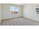 Bedroom features tan carpet, white walls, and trim, with a view of the street at 2256 Base St, Fort Lupton, CO 80621