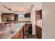 Basement bar area with wooden cabinets, tile countertops, brick wall, and track lighting for a cozy entertainment space at 15835 E Oxford Ave, Aurora, CO 80013