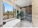 Luxurious bathroom with a soaking tub, elegant chandelier, and serene nature views at 427 Whispering Pines Cir, Breckenridge, CO 80424