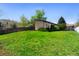 A spacious backyard featuring a lush green lawn, mature trees, and a charming home exterior at 214 Poppy St, Golden, CO 80401