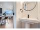 Bright powder room featuring a pedestal sink, round mirror, and views into the main living area at 10151 W 38Th Ave, Wheat Ridge, CO 80033