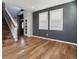 Living room with hardwood floors, stairs, dark accent wall, and large windows with blinds at 3812 Red Deer Trl # D, Broomfield, CO 80020