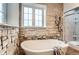 A modern bathroom featuring a standalone tub, stone accent wall, and walk-in shower at 15280 Bannock St, Broomfield, CO 80023