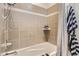 Bathtub area showcasing neutral tile with a decorative accent, a showerhead, and convenient shelving at 15280 Bannock St, Broomfield, CO 80023
