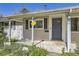Covered front porch features a gray front door, exterior light fixture, and space for seating at 3353 S Glencoe St, Denver, CO 80222