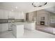 Bright kitchen with white cabinetry, modern appliances, and an island, seamlessly connected to the living room with fireplace at 5755 S Zante Cir, Aurora, CO 80015