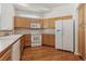 Well-lit kitchen featuring oak cabinets, white appliances, a tile backsplash, and hardwood floors at 12879 E Dickensen Pl, Aurora, CO 80014