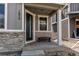 Inviting covered front porch with stone accents, bench seating, and modern design at 1075 Spartan Ave, Berthoud, CO 80513