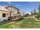 Backyard showcasing a house with large windows, a deck, a lawn, and surrounding trees at 7132 S Tempe Ct, Aurora, CO 80016