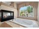 A luxurious bathtub with a fireplace and a beautiful garden view window at 7132 S Tempe Ct, Aurora, CO 80016