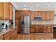 Kitchen with stainless steel appliances, wood cabinets, and stone countertops at 7132 S Tempe Ct, Aurora, CO 80016