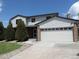 Two-story home with white siding, a brick facade, and an attached two-car garage under a blue sky at 7753 W Plymouth S Pl, Littleton, CO 80128