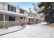 Charming home exterior with covered patio and view of the lush, snow-covered backyard at 6885 E Briarwood Cir, Centennial, CO 80112