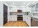 Well-lit kitchen featuring stainless steel appliances, white cabinetry, modern countertops and stylish wood-look floors at 6885 E Briarwood Cir, Centennial, CO 80112