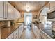 Bright kitchen featuring white cabinets, granite counters, and tiled floors open to the dining area at 8450 Everett Way # D, Arvada, CO 80005