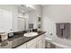 Bright bathroom with a granite countertop, white cabinets, and shower with glass door at 10976 Lewiston St, Commerce City, CO 80022