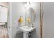 Well-lit powder room featuring pedestal sink, oval mirror, and neutral wall color at 10976 Lewiston St, Commerce City, CO 80022