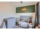 Sweet Bedroom featuring a crib, green accent wall, and dresser with changing table at 7912 S Depew St # A, Littleton, CO 80128