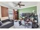 Cozy bedroom featuring a large desk, monitors, and a comfortable gray couch with brown curtains and a ceiling fan at 7912 S Depew St # A, Littleton, CO 80128