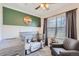 Charming Bedroom featuring a crib, chair, and a green accent wall at 7912 S Depew St # A, Littleton, CO 80128