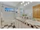 Bright bathroom with double sinks, stylish checkerboard floor, and ample natural light at 18885 E Union Dr, Aurora, CO 80015