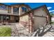 Angled view of charming tan home with brick accents and a three car garage and front porch at 18885 E Union Dr, Aurora, CO 80015